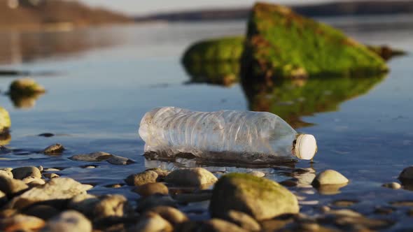 A Plastic Bottle is Thrown Away on the River Bank