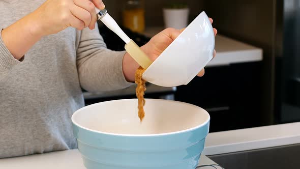 Woman adding ingredients to bowl for baking