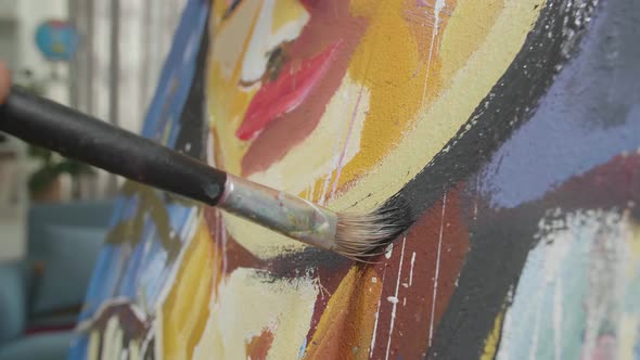Close Up Of A Hand Holding Paintbrush Mixed Colour And Painting A Girl's Face On The Canvas