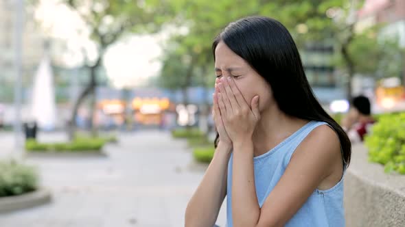 Woman sneeze and cough at outdoor in Hong Kong city 