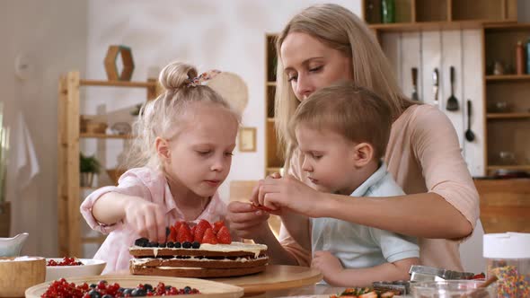 Caucasian Mom and Kids Topping Layered Cake with Fresh Berries