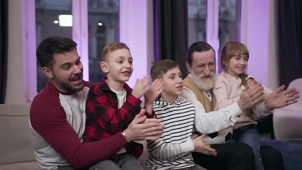 Kids, their Father and Grandfather which Emotionally Watching Football Game