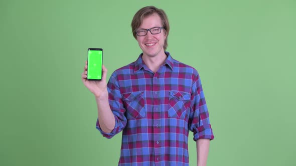 Happy Young Handsome Hipster Man Pointing and Showing Phone