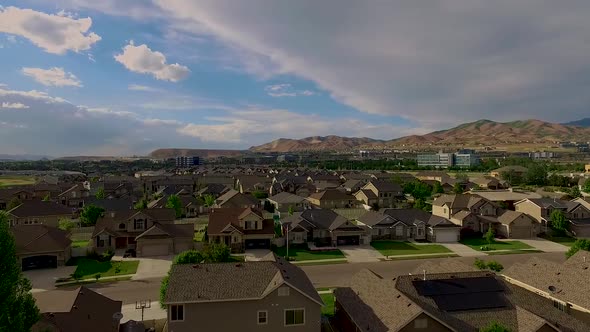 Aerial view of a suburban neighborhood with nice houses and a business park and mountains in the dis