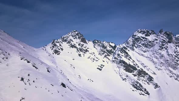 Aerial drone shot flying through bright white snow and mountains covered in clouds above the ski res