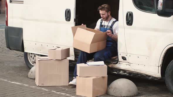 Delivery Man Checking Commodity of Paper Box Outside