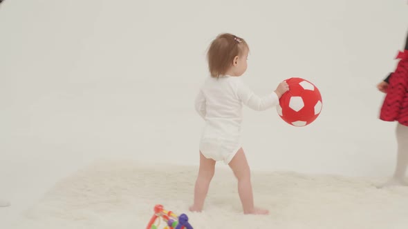 Two Little Girls Playing Toys in a White Room