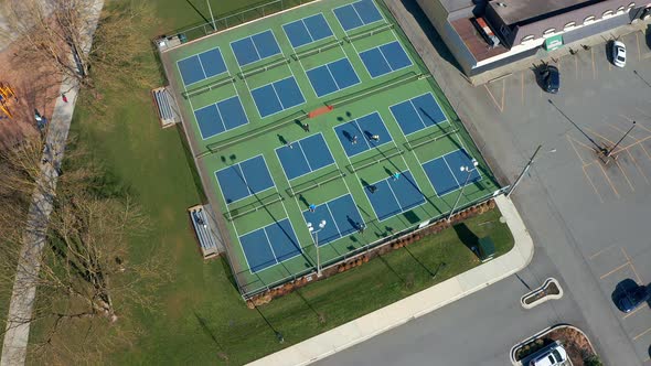 Birds Eye View of Tennis Players in a City Park, Drone Truck Left past the Sports Courts