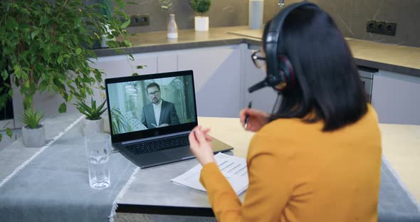Woman in Headset Holding Video Conference with Male Colleague