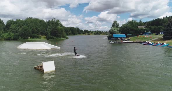Wakeboarding in a Lake Near the Forest, Adult Man Surfs on the Water, Ride on a Wakeboarding Board