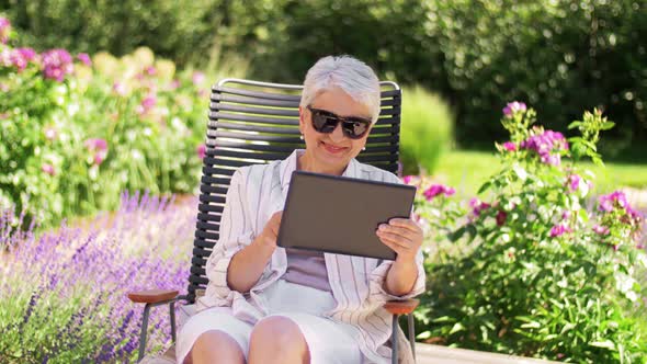 Happy Senior Woman with Tablet Pc at Summer Garden