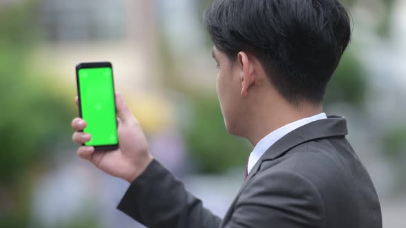 Young Handsome Asian Businessman Showing Phone in the Streets Outdoors