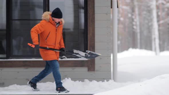 Man in Jacket Cleans Track From Snow with Shovel in Yard