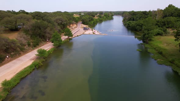 Aerial footage of the Blanco River i Blanco Texas. Drone approaches a dam with people swimming