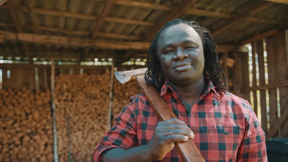 African Lumberjack in the Store with Stacked Logs for Winter Nodding His Head with Smile