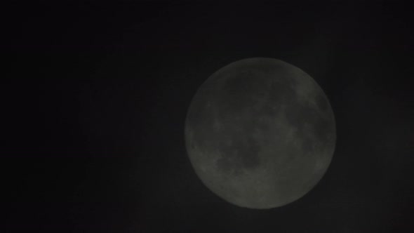 Clouds passing by the full moon, real time shot. Full moon at night with clouds in real time.