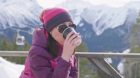 Woman Drinking Warm Tea in the Rustic Wooden Terrace on Mountain. Girl Is Enjoying the Panoramic