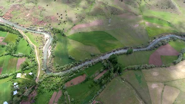 Little Village Houses Surrounded by Green Meadows and River in Fields