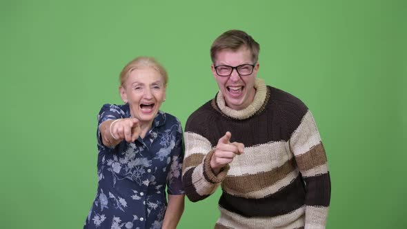 Happy Grandmother and Grandson Laughing While Pointing at Camera Together