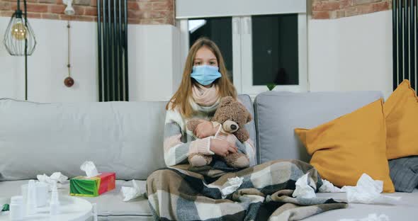 Teen Girl in Medical Mask in Living-Room on Home Self Isolation During Disease, Sickness