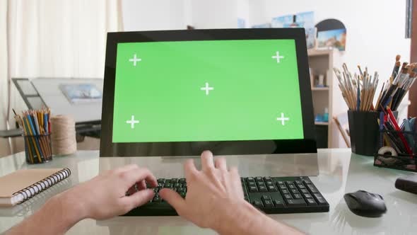 View on Male Hands Working on a Computer with Green Screen on a Glass Table