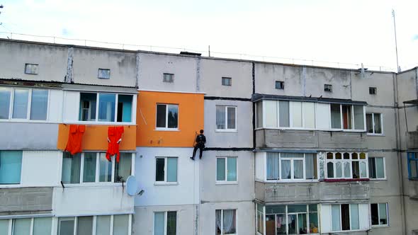 Painting and Decorating Buildings. Worker on a Construction Site of a High-rise Building. Dangerous