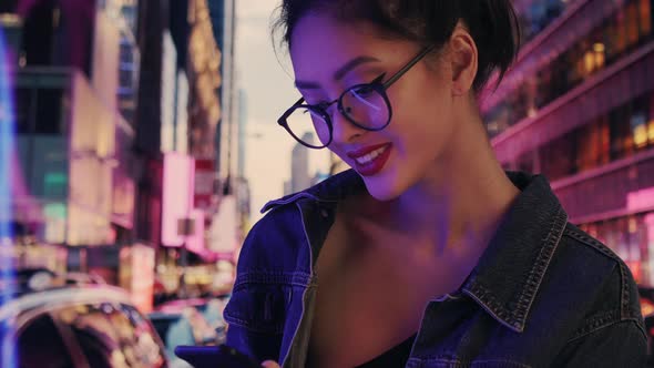 Woman Using a Smartphone in the City at Night