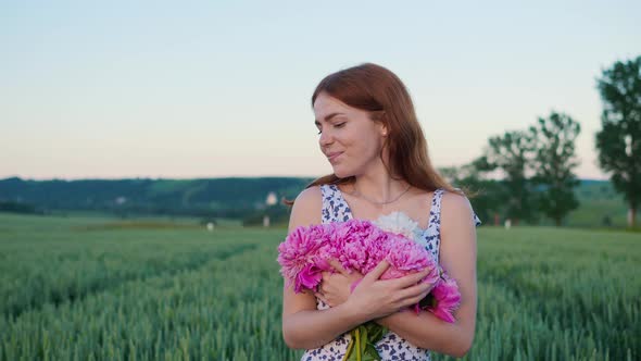 Woman Holding Pink Flowers Peonies Walking in the Field Enjoying Freedom Sunset