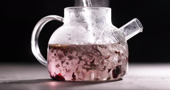 Process of Brewing Red Tea in Glass Transparent Teapot at Dark Background