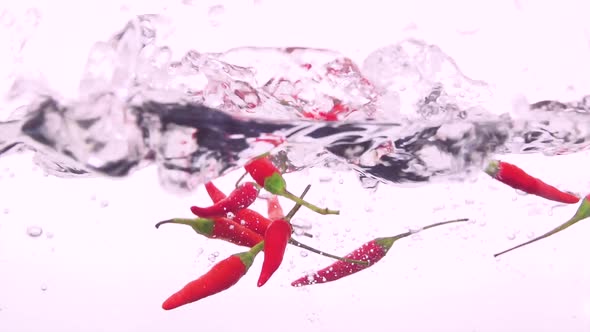 Red chili peppers falling into water