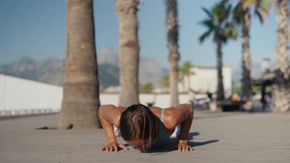 Young Muscular Woman Training Chest in Sunny Morning in City Street