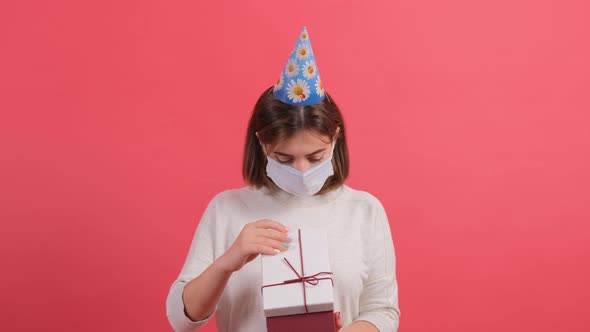 Close Up of an Optimistic Girl with Medical Mask on Face Opening Gift Box