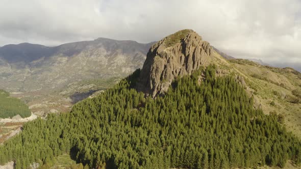 Aerial shot of a mountain with a rock formation on top surrounded by woodland in Patagonia, Argentin