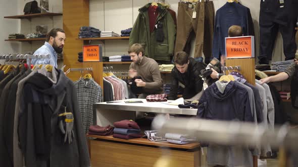 Wide Shot of Caucasian Men and Women Fighting for Clothes in Shop During Black Friday Sales. Male