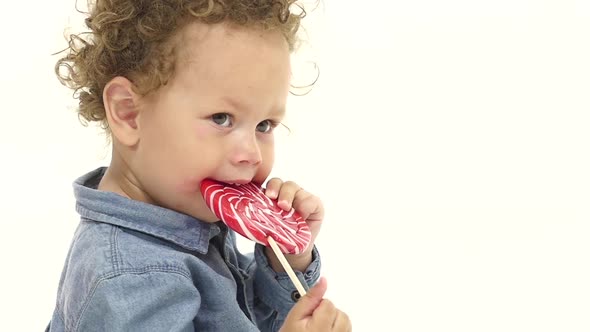 Child Licks a Candy. White Background. Slow Motion. Close Up
