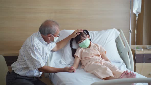 Asian young little girl kid wearing mask lying on bed in recovery room from curing the COVID 19.