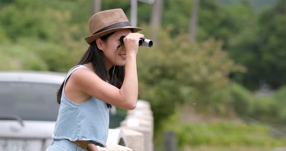 Happy woman traveling and look though the binocular at outdoor landscape