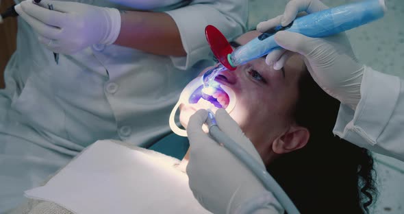 Woman Dentist In Medical Gloves Works with a Patient Girl in a Dental Office Braces Installation and