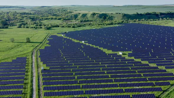 Aerial view on Solar Power Station in Green Field near River at Sunny Day