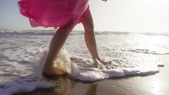 RED Camera Shooting Legs of the Woman Walking Along Sea Shore with White Waves