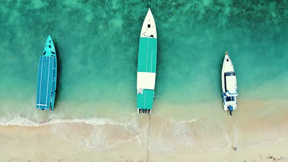 Aerial top down view of three long boats parked on the seashore.