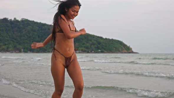 Young Woman Dancing And Skipping In Sea At Sunset