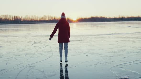 Woman Ice Skating on Frozen Lake at Sunset