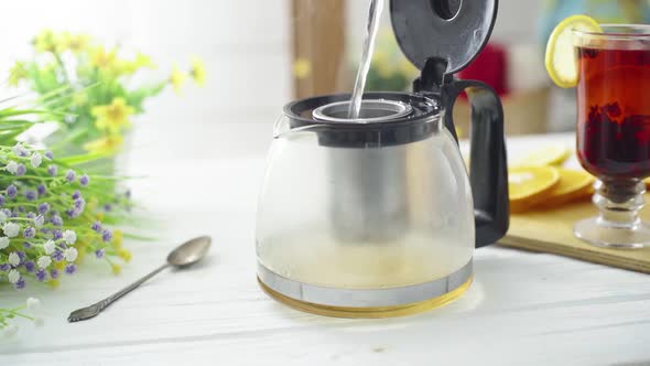 Tea is Poured Into a Transparent Pot on a Wooden Table