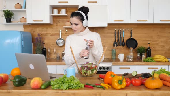 People And Technology Concept. Girl Cooking In Kitchen While Using Laptop Looking For Recipe