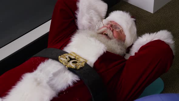 Santa Claus trying to do a sit up in gym