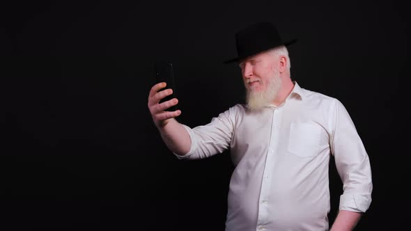 Old Man with Albinism Using Phone and Taking Selfie on Black Background.