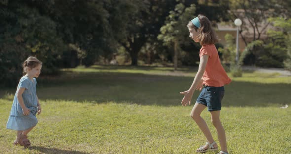 Two young girls playing together witha big white god outside on the grass