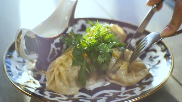 Macro Person Cuts Tatar Dumplings with Knife Fork on Table