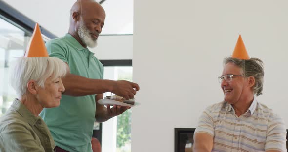 Happy senior diverse people at birthday party with cake at retirement home